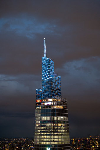 Upper side view of One Vanderbilt skyscrapers in colorful light with glassy facades against cloudy night sky in New York city