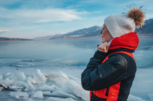 Young woman tourist looking on frozen lake in Kyrgyzstan at winter season