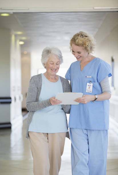 istock Nurse and aging patient reading chart in hospital corridor 184312589