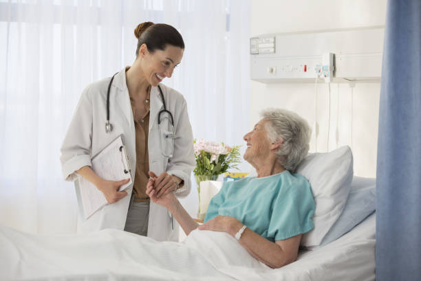 Doctor and senior patient talking in hospital room stock photo