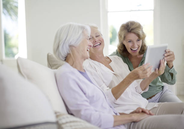 starszych kobiet za pomocą cyfrowego tabletu na kanapie - ipad 3 ipad white caucasian zdjęcia i obrazy z banku zdjęć