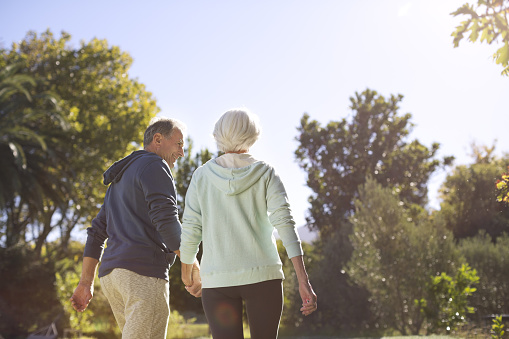 Rear view of a senior couple going for a relaxing walk in the park holding hands