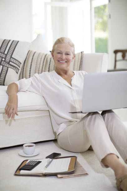 istock Senior woman using laptop on living room floor 184312830