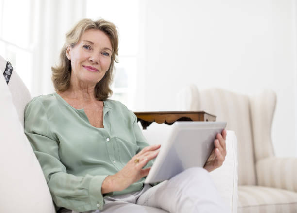 istock Portrait of senior woman using digital tablet on sofa 184312857