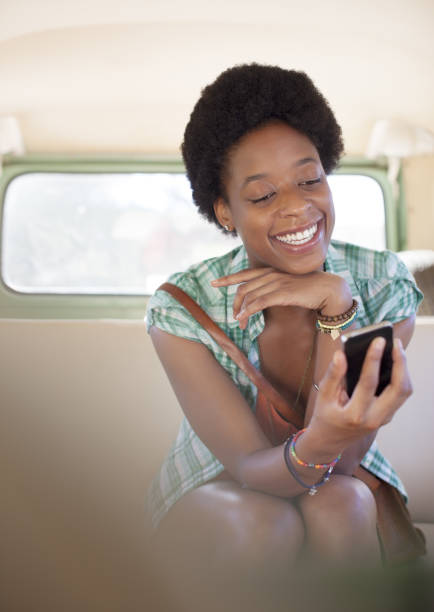 istock Woman using cell phone in back seat of camper van 184313003