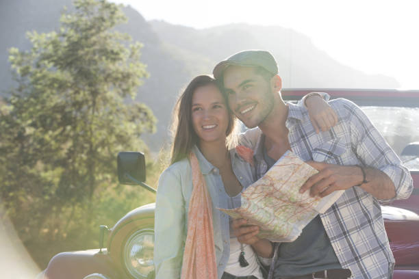 istock Smiling couple with map next to sport utility vehicle 184313042