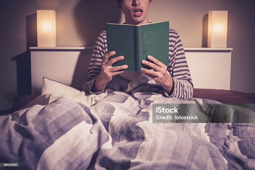 Junger Mann lesen im Bett - Lizenzfrei Bett Stock-Foto