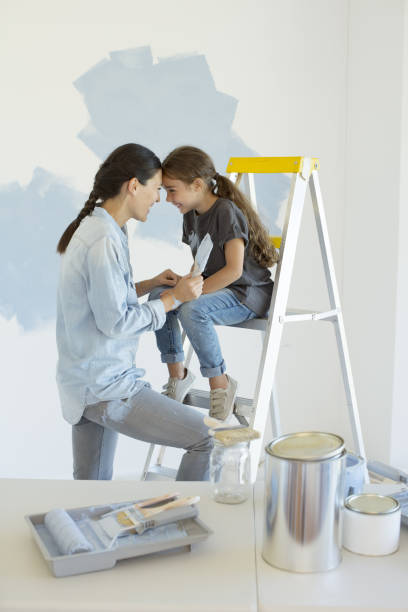 istock Mother and daughter painting wall blue 184313165