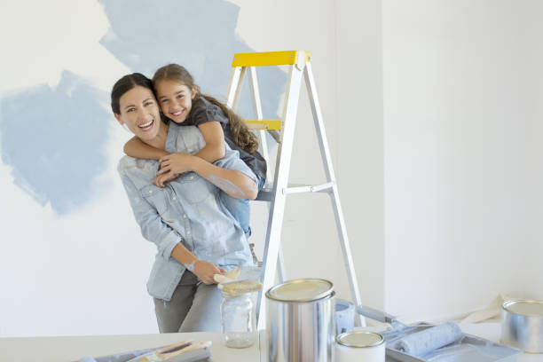Portrait of mother and daughter hugging near paint supplies  cheek to cheek stock pictures, royalty-free photos & images