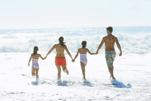 família correr no surf na praia - ankle deep in water imagens e fotografias de stock