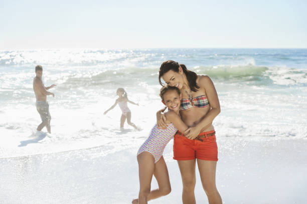 istock Mother and daughter hugging on beach 184313292