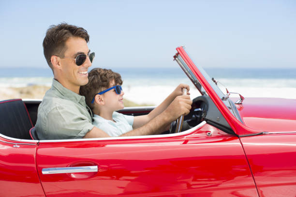 istock Father and son driving convertible at beach 184313341