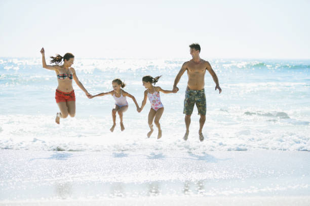 istock Family jumping in waves on beach 184313448