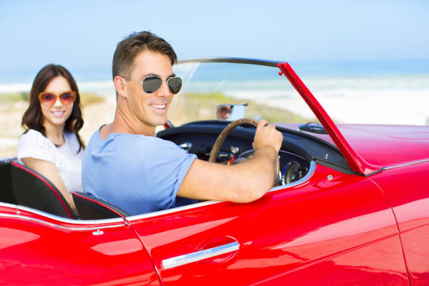 istock Couple driving convertible on beach 184313452
