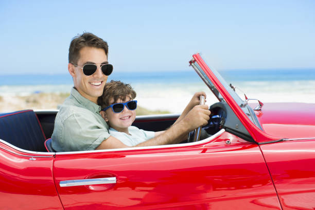 istock Father and son driving convertible on beach 184313467