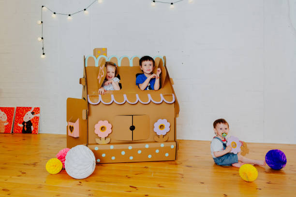 istock Joyful siblings running after each other and around cardboard house. 1843135851
