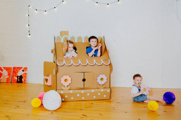 istock Joyful siblings running after each other and around cardboard house. 1843135854