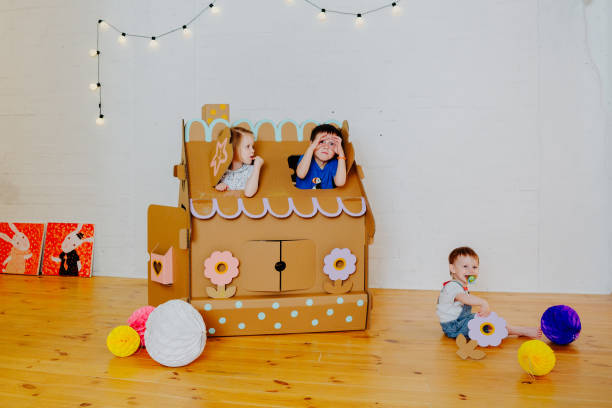 istock Joyful siblings running after each other and around cardboard house. 1843135855