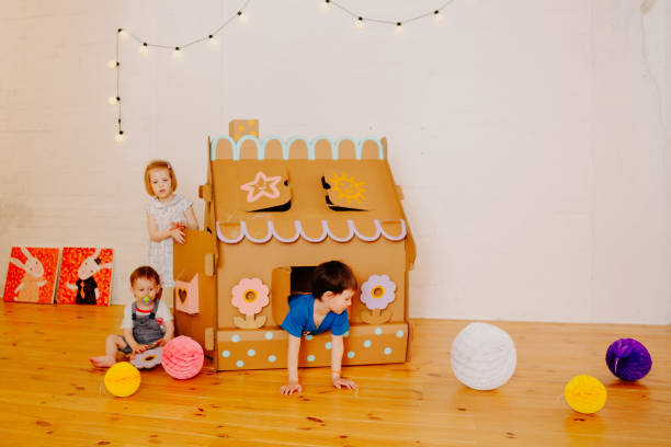 istock Joyful siblings running after each other and around cardboard house. 1843135856
