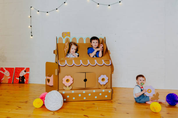 istock Joyful siblings running after each other and around cardboard house. 1843135859