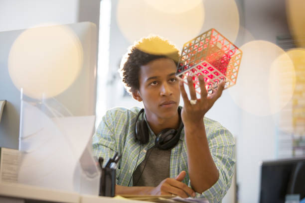businessman examining cube at desk in office - innovation stockfoto's en -beelden