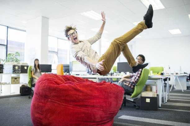 бизнесмен прыжки в кресле-мешке в офисе - creativity inspiration humor business стоковые фото и изображения