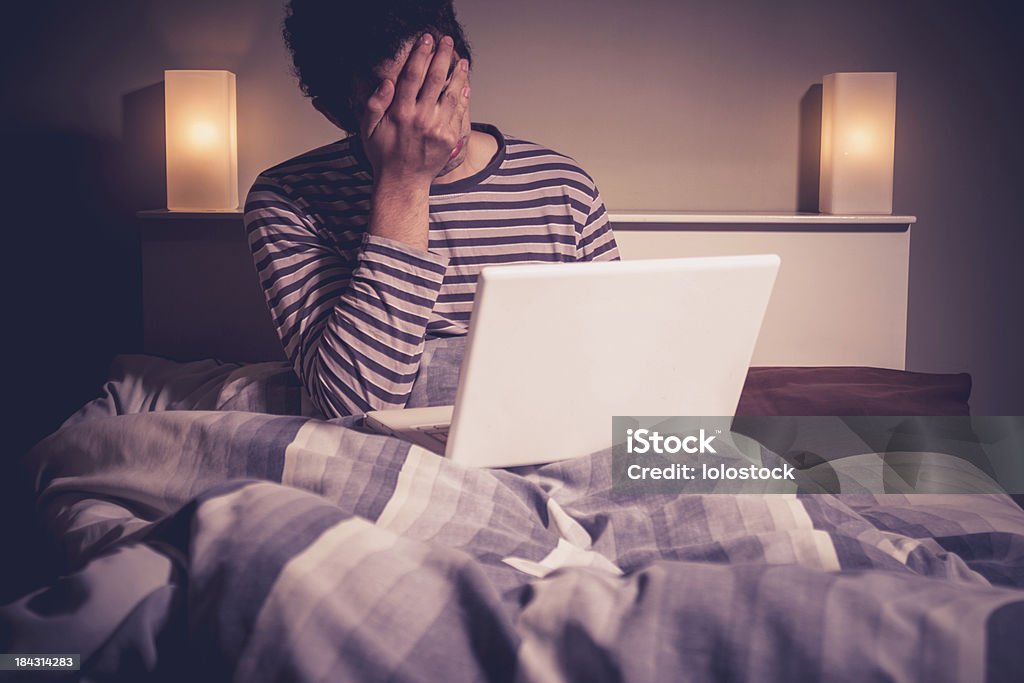 Homem triste na cama com o laptop - Foto de stock de Cama royalty-free
