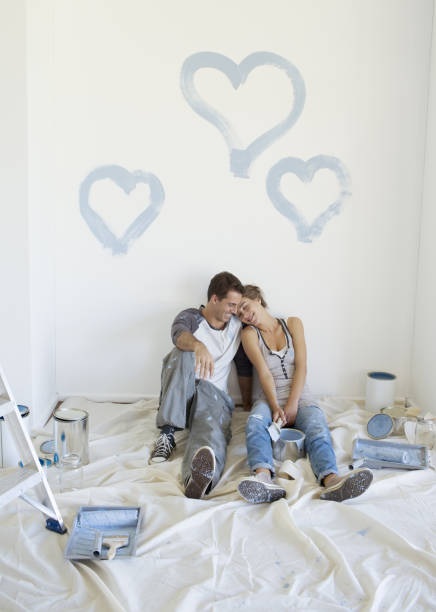 istock Couple painting blue hearts on wall 184314598