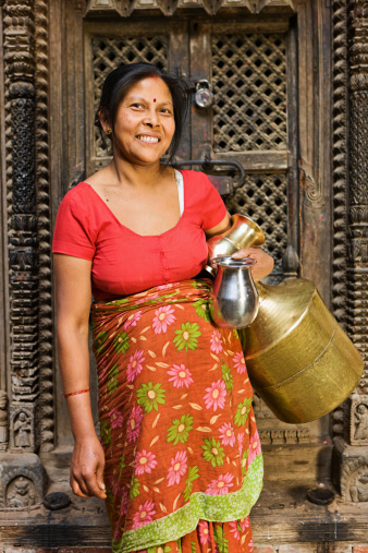 Nepali woman carrying water from city well.