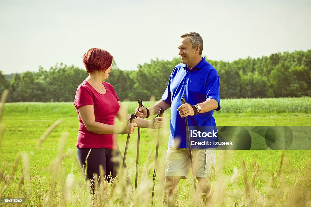 Active seniors doing nordic walking Mature couple enjoying nordic walking in a countyside. Looking at each other and smiling. 50-54 Years Stock Photo