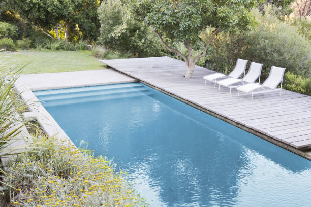 istock Wooden deck and lounge chairs by swimming pool 184315995