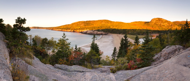 A large panorama of Sand Beach, The Beehive, Gorham Mountain, and the Thunder Hole coastline down to Otter Point as seen from the pink granite rocks of Great Head just after sunrise on an Autumn morning.