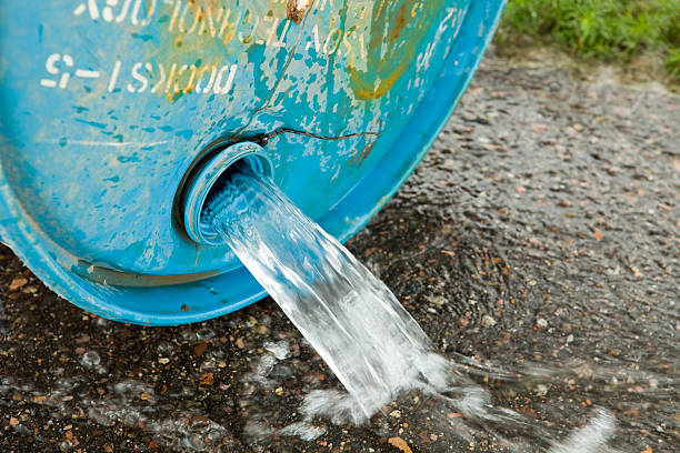 Blue, plastic water barrel reused for collecting and storing rainwater for watering plants full with water in bright sunlight in the garden