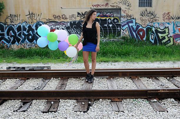 Young woman with balloons in the form of a heart on the background of a love tunnel, Ukraine, Klevan.