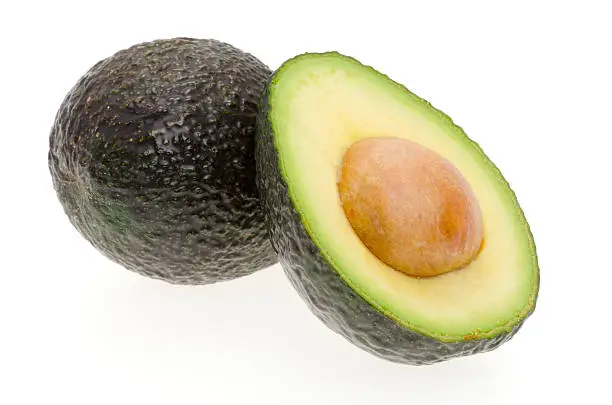A whole avocado and another cut in half - shot in the studio with a white background