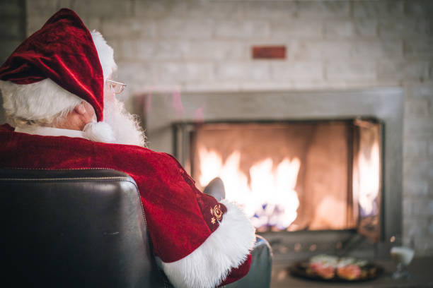 istock Santa Claus relaxes in front of fireplace 1843182699