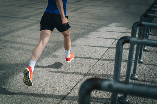 Low angle view of  trail runner bounding along urban pathway