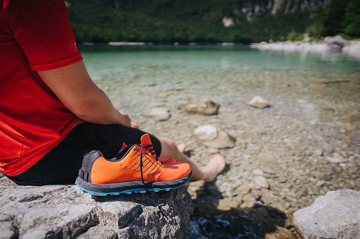 Trail runner pauses on lake shore and looks off to distant scene