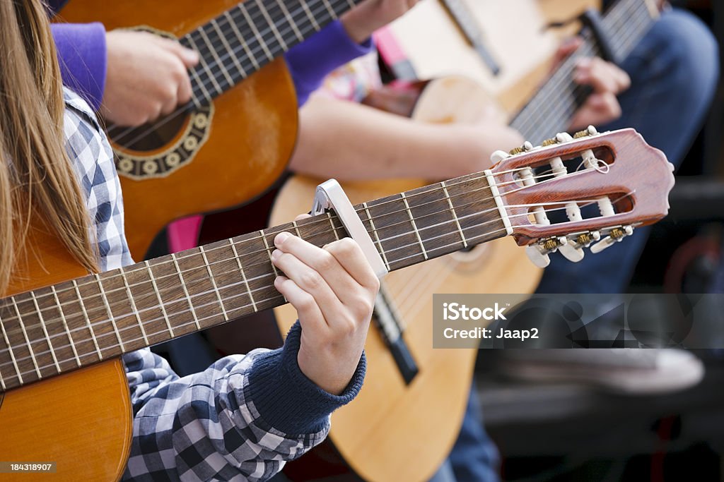 Close-up of children playing acoustic guitar outdoors, shallow DOF "Close-up of acoustic guitars being played by children at an outdoor performance. Shallow DOF.Canon 1Ds Mark III + 169 mm @ ISO 200 from RAW, cropped & downsized" Acoustic Guitar Stock Photo