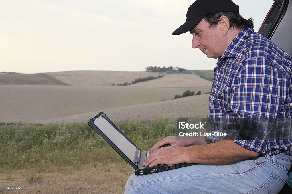 Agriculteur à l'aide d'ordinateur dans la campagne - Photo de Adulte libre de droits