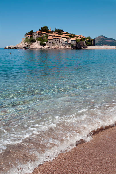 Cristal clear water of St. Stefan The clearest water of Montenegrin coast is around town - hotel on Island of St. Stefan.  During morning, breze of fresh wind produce the smalest waves, splashing the red sand of the Beach.  Slective Focus stock pictures, royalty-free photos & images