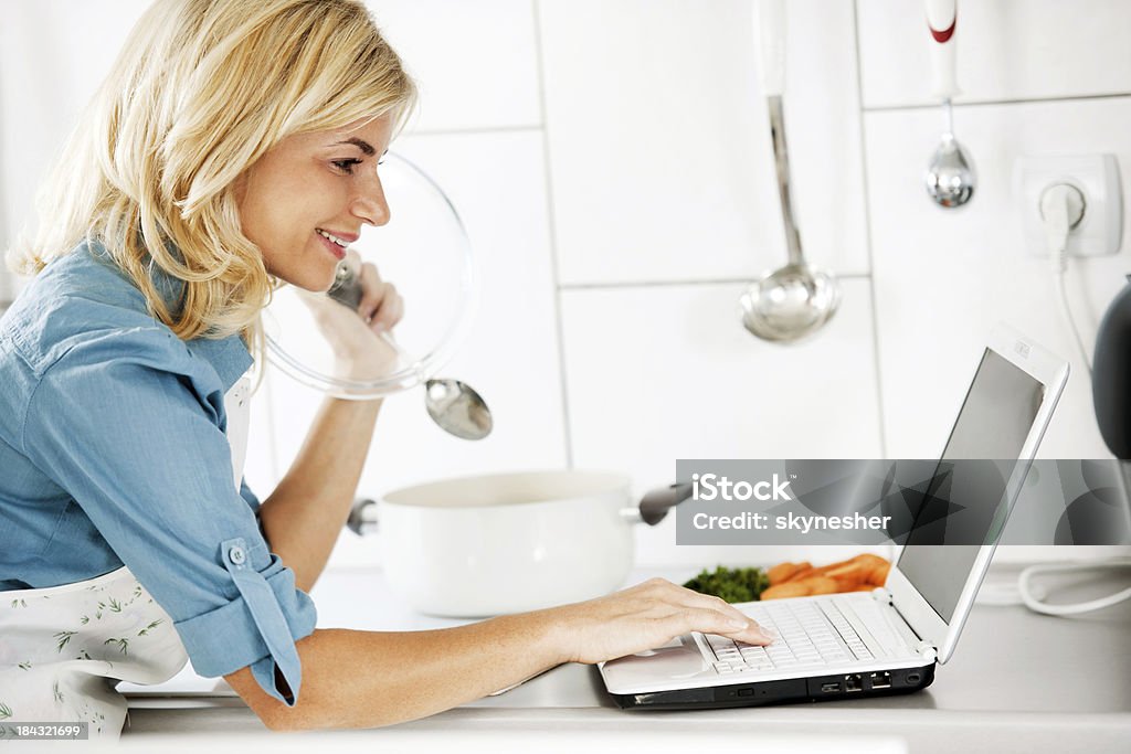 Красивая женщина приготовления пищи и глядя на Рецепт в Интернете. - Стоковые фото Белый роялти-фри