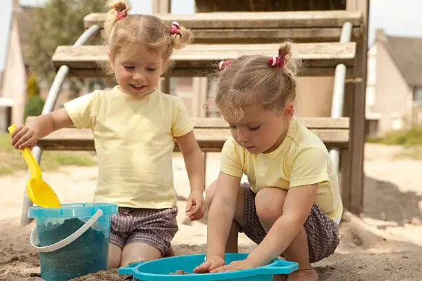 Twin girls with playing in sandbox.