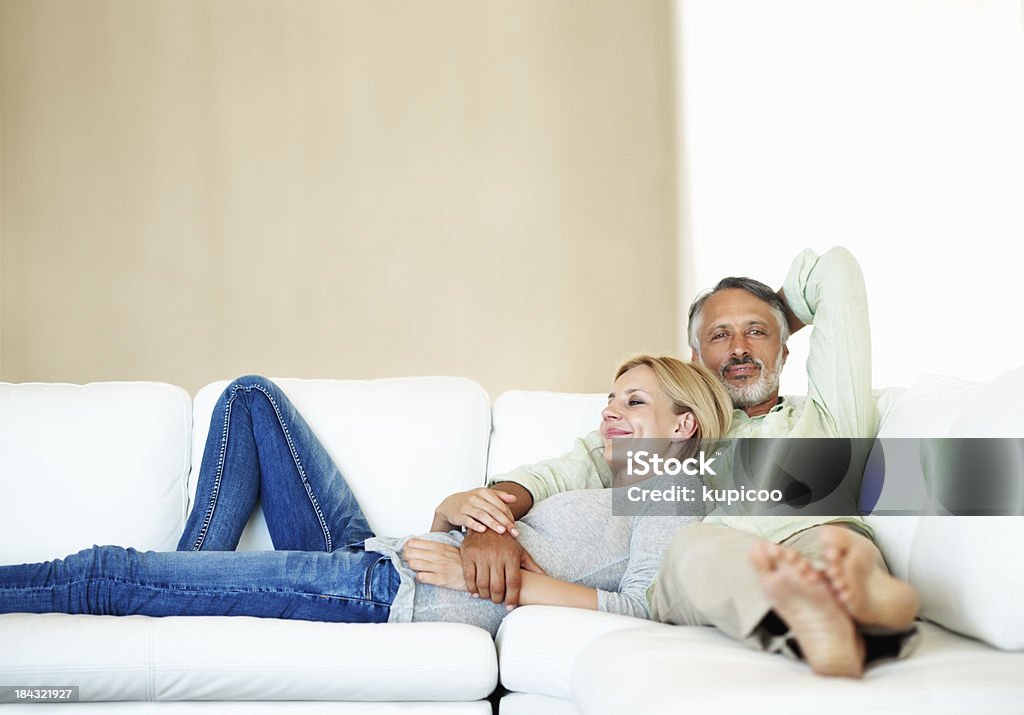 Mature couple resting on sofa Portrait of happy mature couple lying together on couch at home Mature Couple Stock Photo