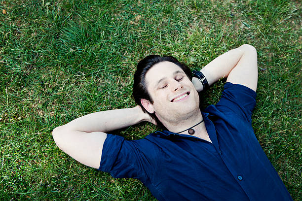 istock Handsome Young Man Relaxing and Smiling in the Grass 184322504