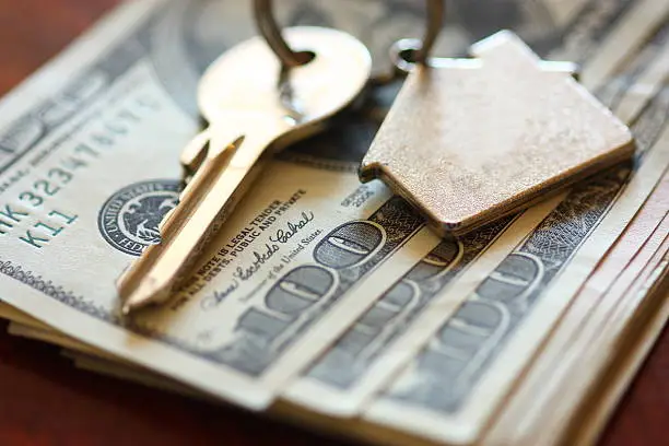 Photo of Set of house keys laying on hundred dollar bills