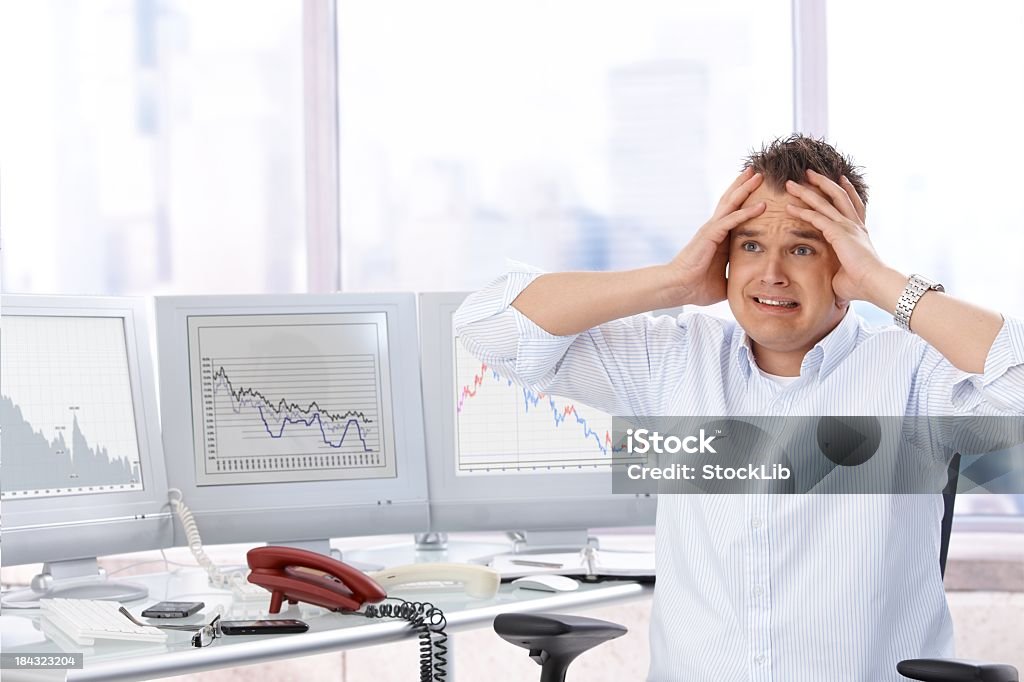 Overworked businessman Tired young businessman sitting at desk, head in hands, looking away. Hopeless expression. 20-29 Years Stock Photo
