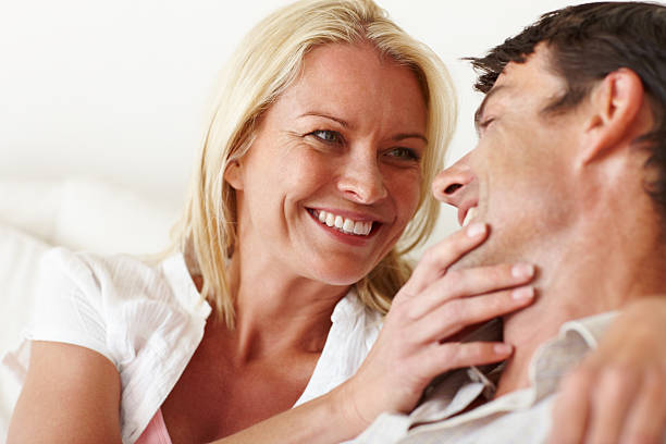 Cute dark haired couple cuddling smiling at the camera isolated on a white background