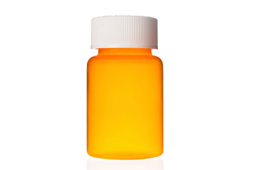Close-up of empty unlabelled orange pill bottle on glass