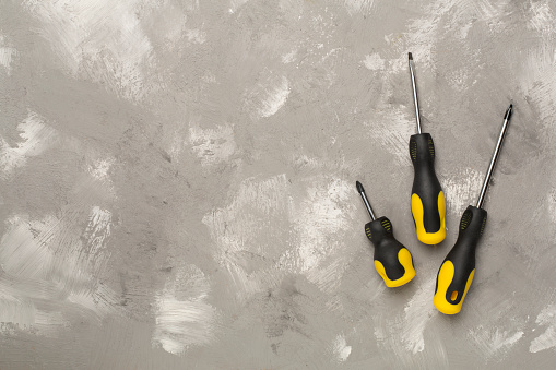 Screwdrivers on concrete background, top view